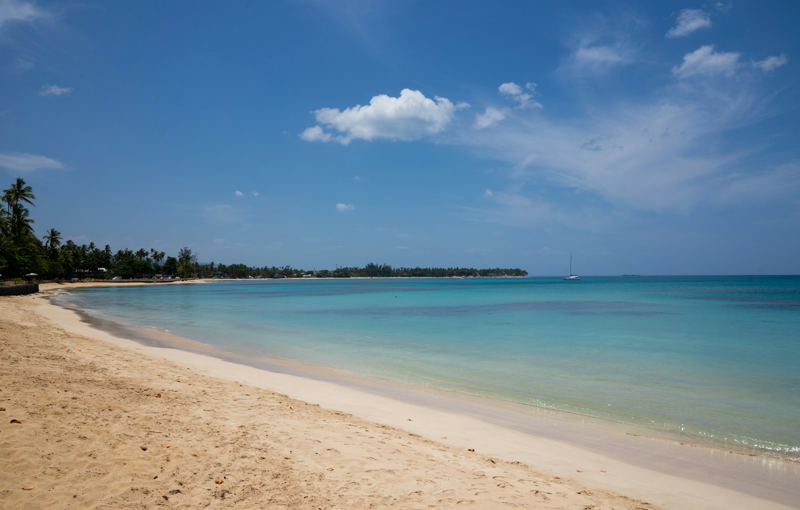 Quiet Caribbean beach with sailboat on turquoise water