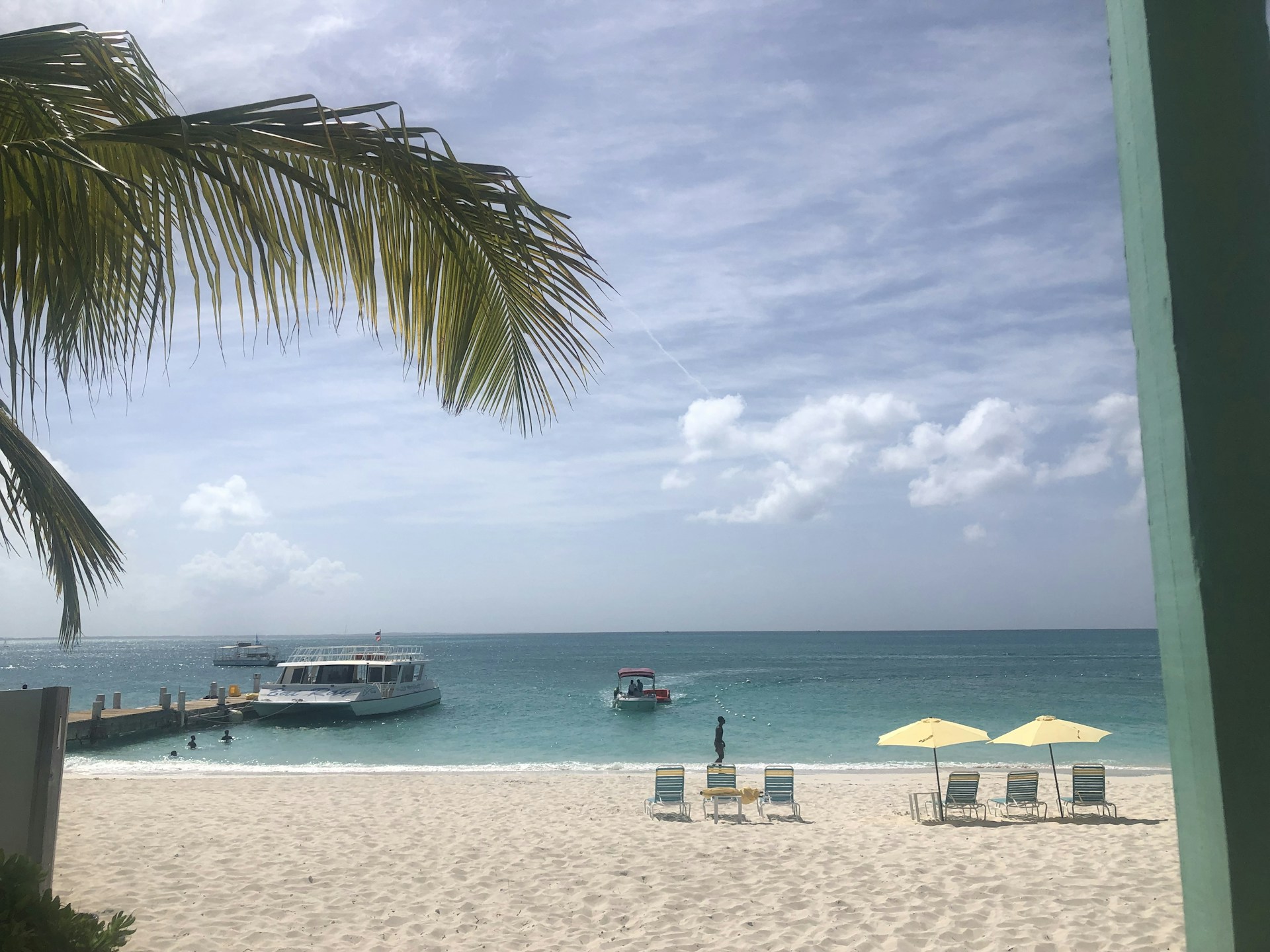 Turquoise Caribbean beach with lounge chairs and pier
